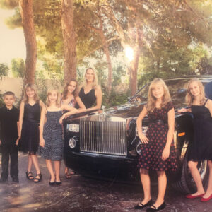 Family photo with all 8 kids in front of a luxury car