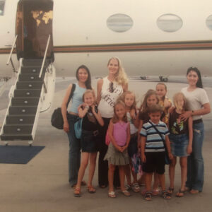 Family photo with all 8 kids in front of a private jet